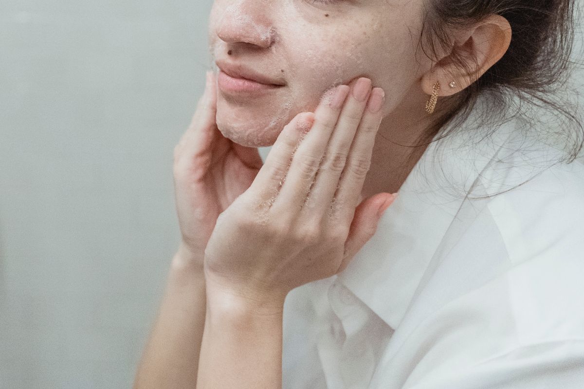 Person cleansing their face at a mirror
