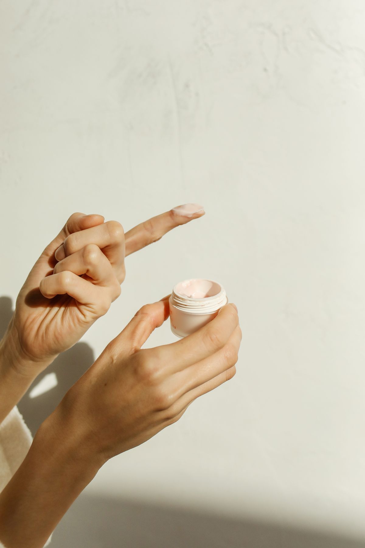Hands opening a jar of moisturiser