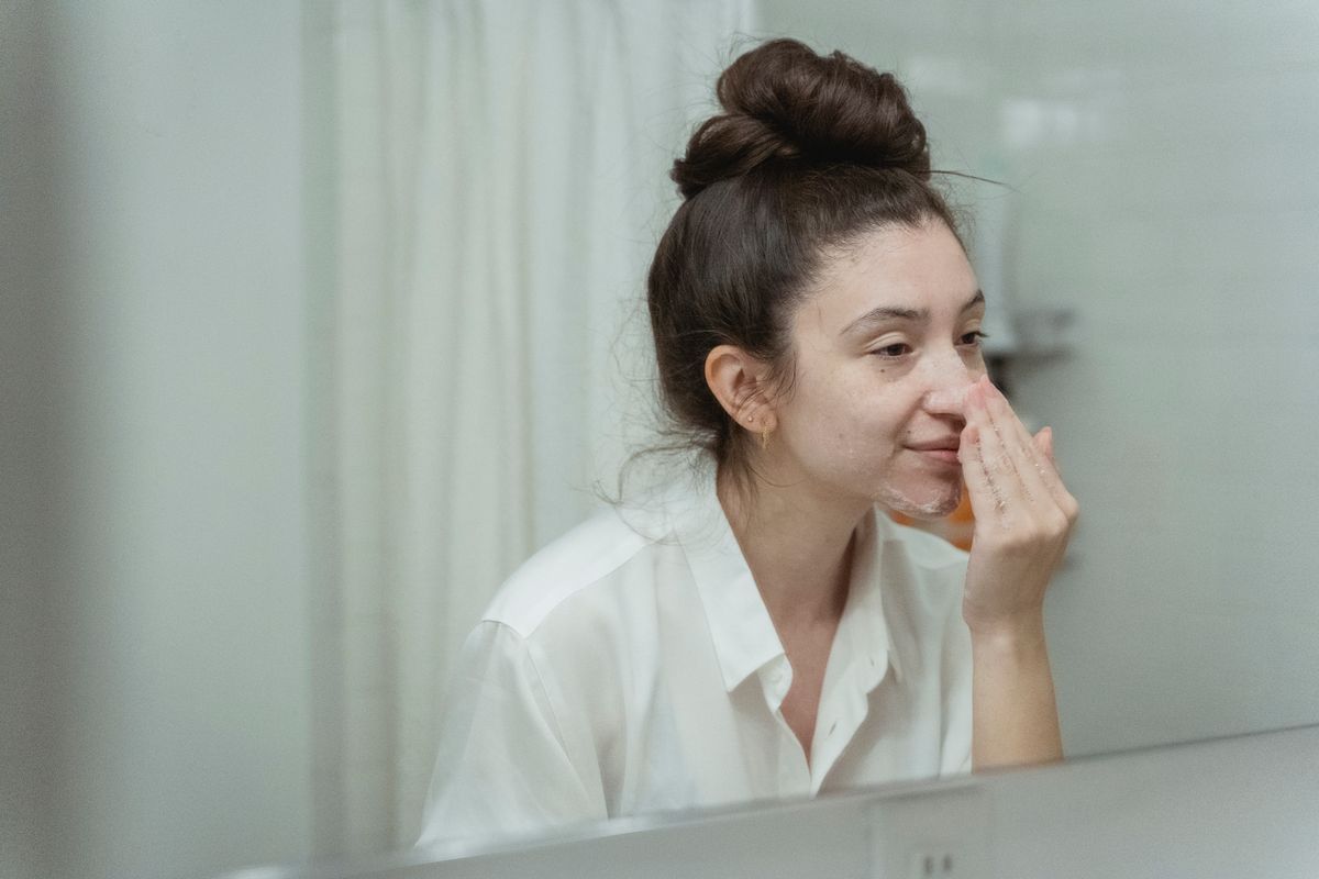 Person cleansing their face at a mirror