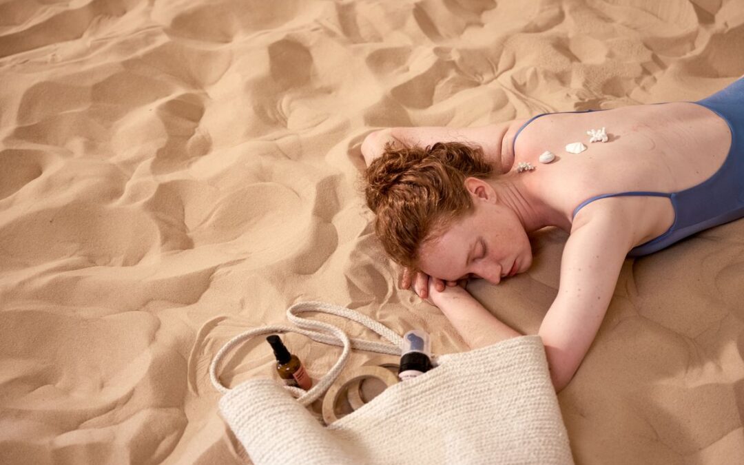 Person lying on a beach with cream on their back