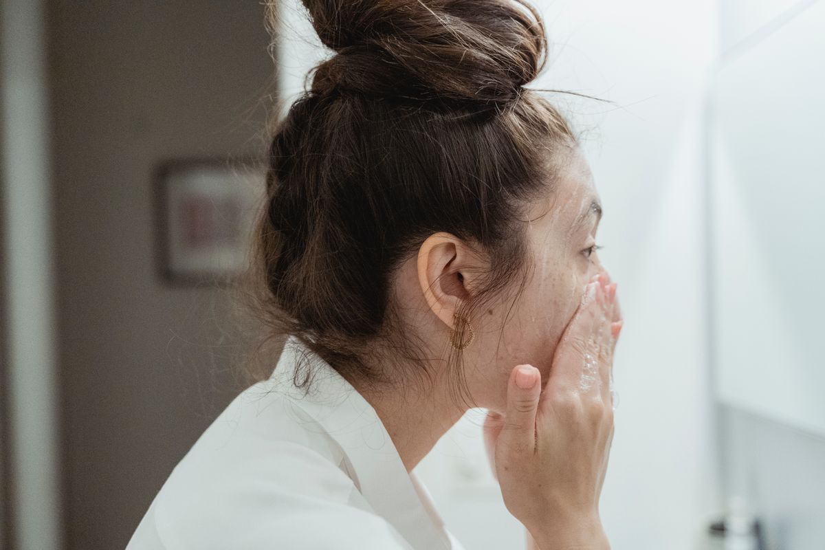 Person cleansing their face at a mirror