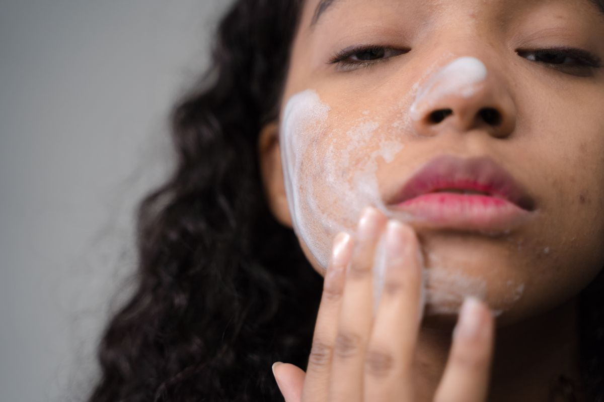 Person cleansing their face at a mirror