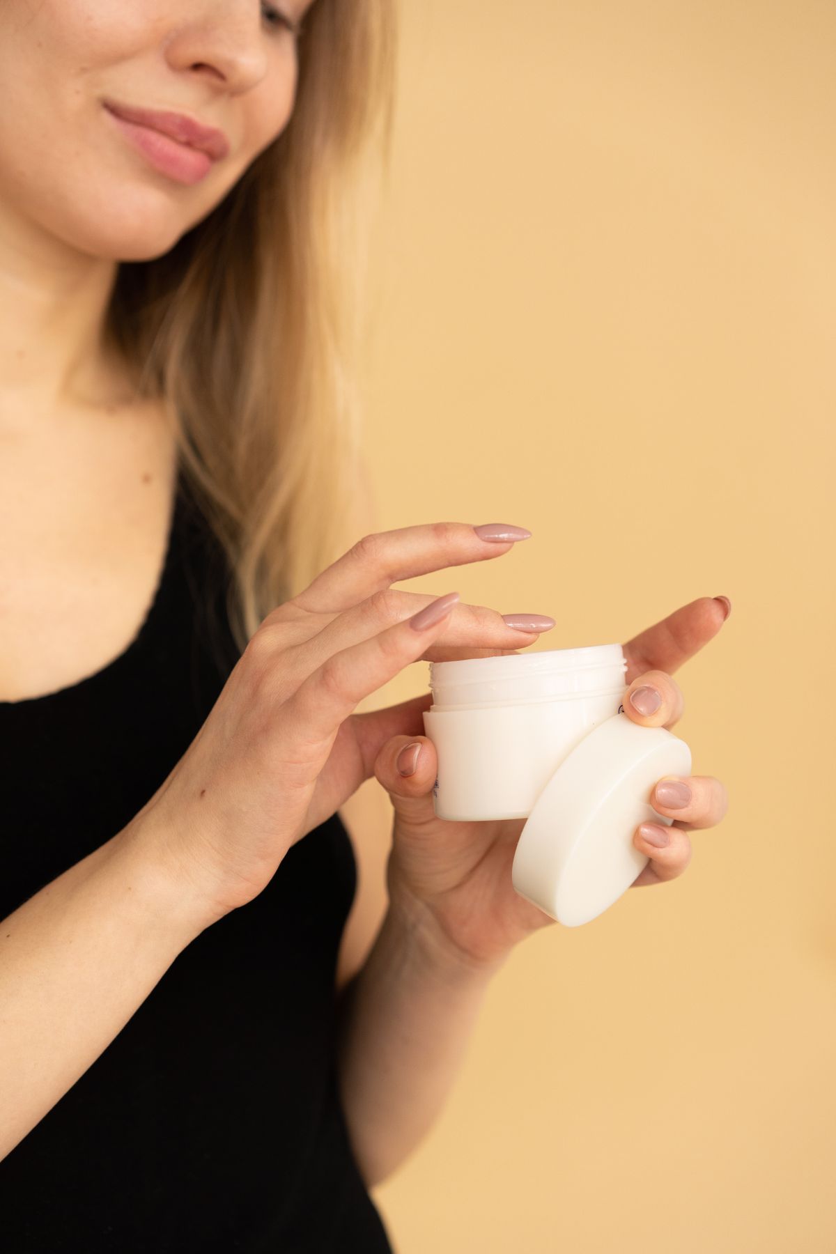Person holding a cream jar against an orange background