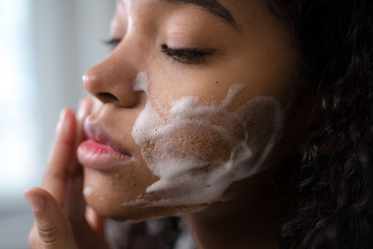 Person cleansing their face at a mirror