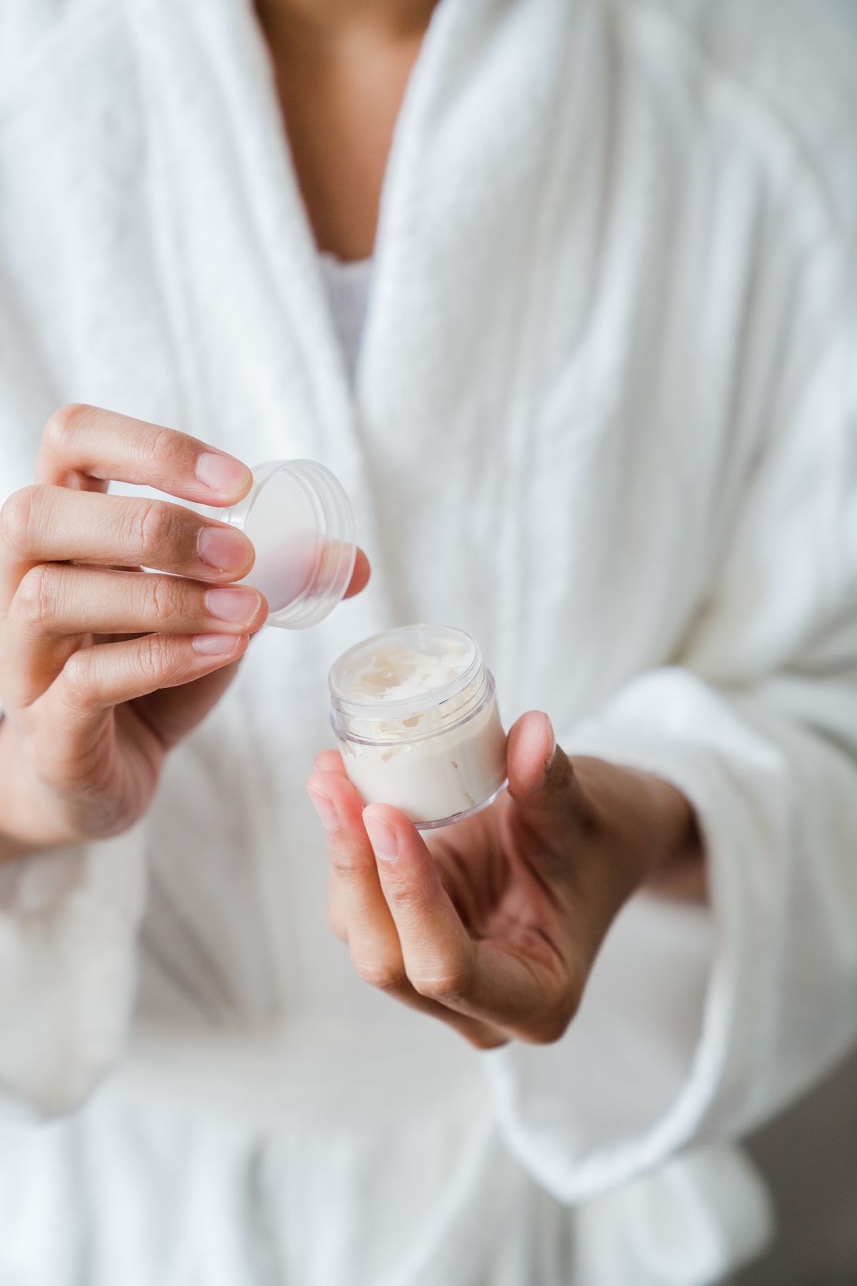 Hands holding a jar of skincare cream