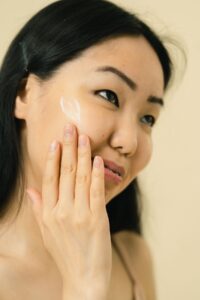 Person applying facial skincare cream
