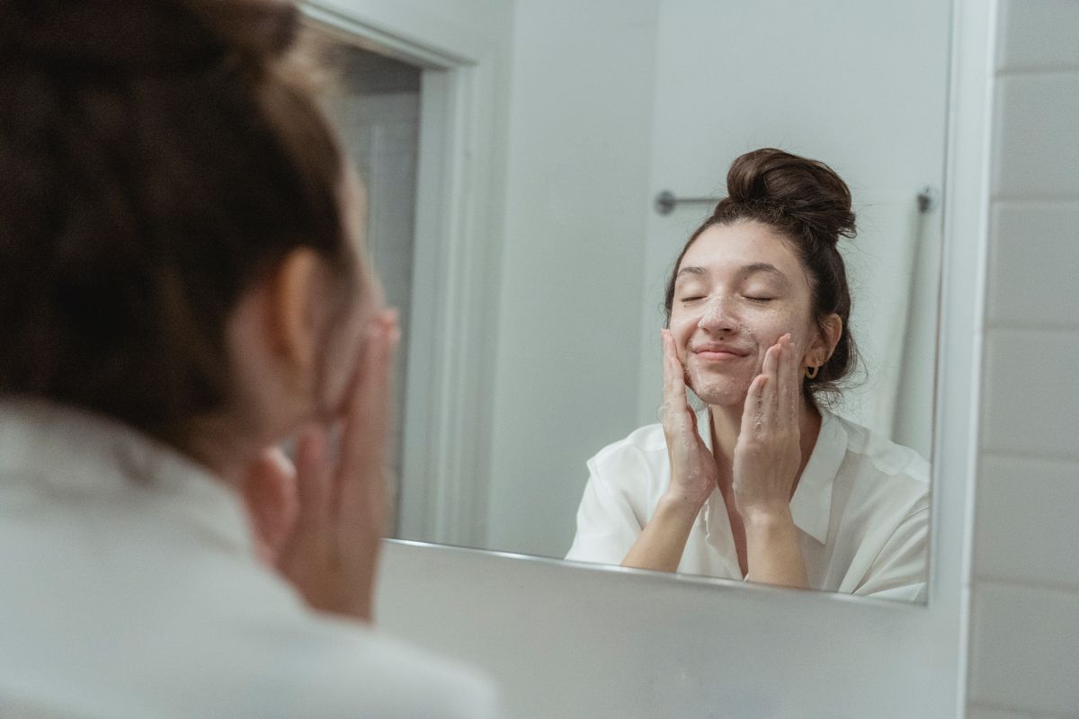 Person cleansing their face at a mirror