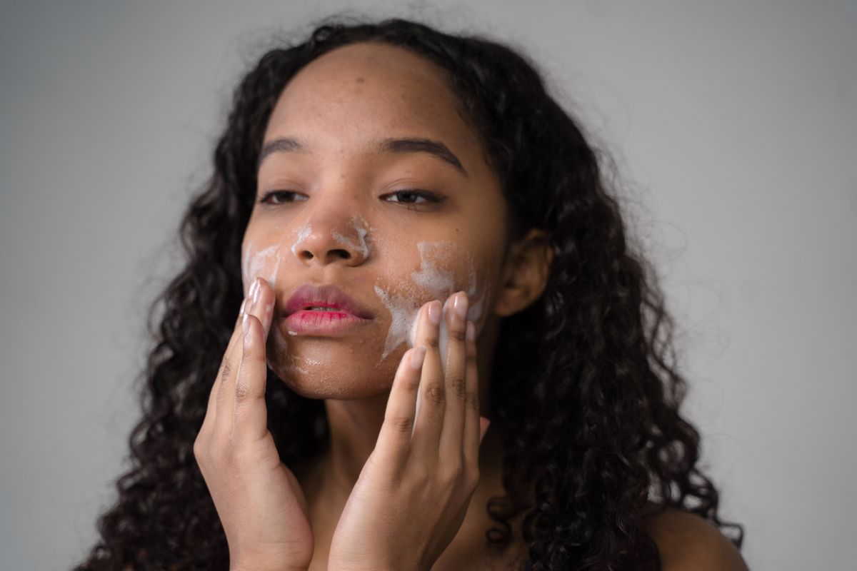 Person cleansing their face at a mirror