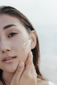 Person applying facial skincare cream