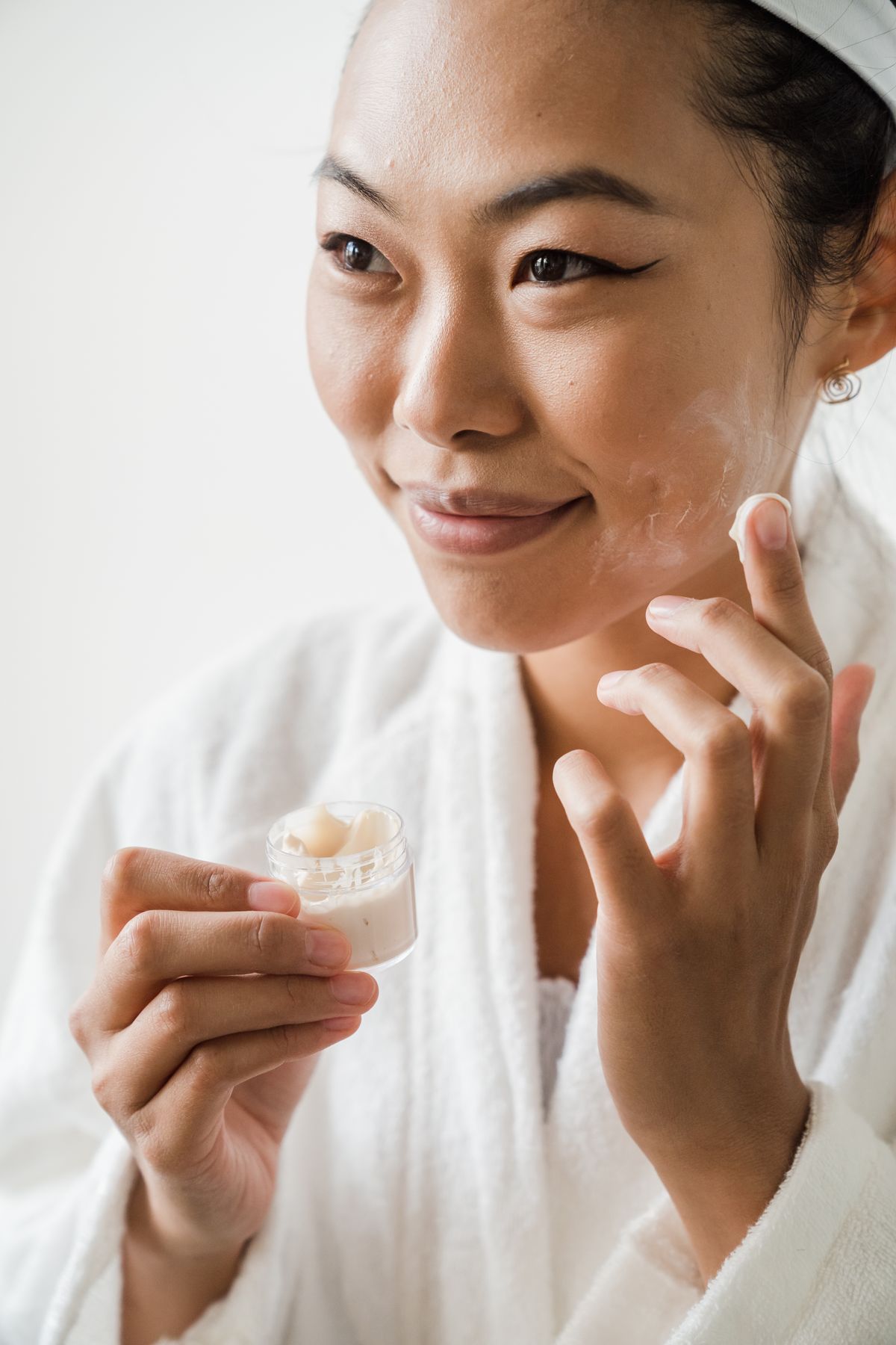 Person applying facial skincare cream