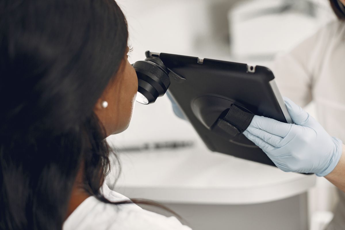 Gloved practitioner holding a digital skin observation device and tablet